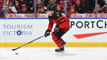 Cale Makar skates with the puck by his stick, wearing a red jersey