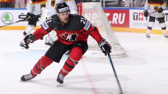 Brayden Point in a red Canada jersey skates into the corner of the rink