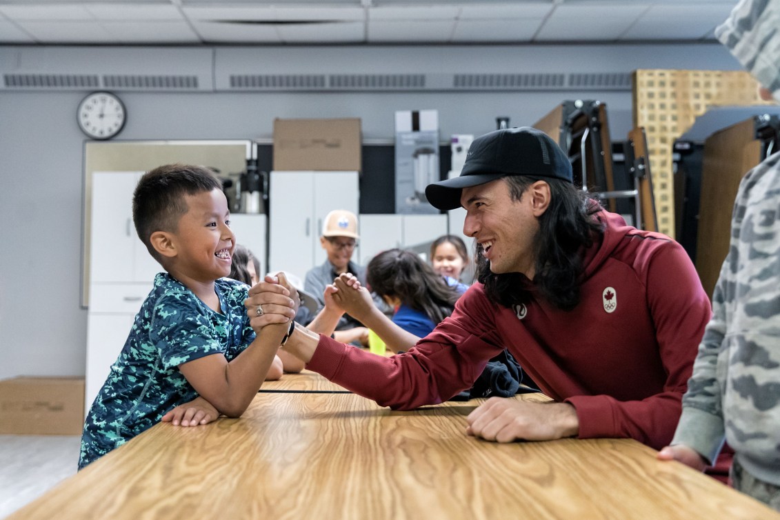 Liam Gill arm wrestles with a student during a school visit