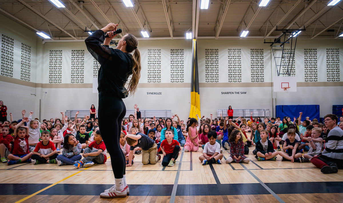 Paige Crozon speaks in front of an assembly of students
