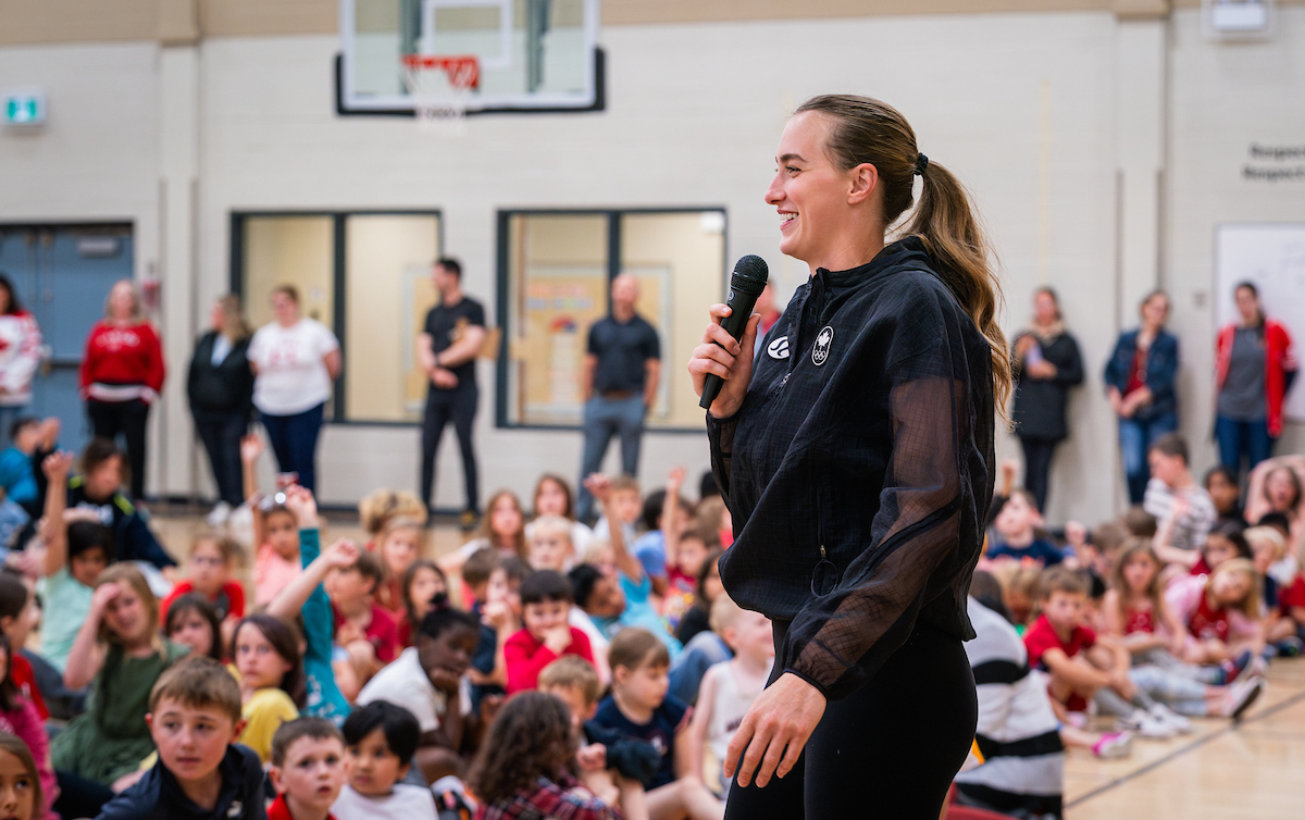 Paige Crozon speaks in front of an assembly of students