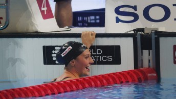 Summer McIntosh smiles at the end of a race while hanging on to the wall of the pool