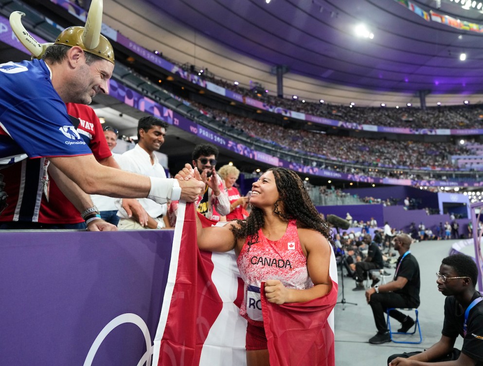 Camryn Rogers shakes hands with fans in the stands at the Paris 2024 Olympic Games