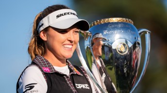 Brooke Henderson smiles while holding a large silver trophy