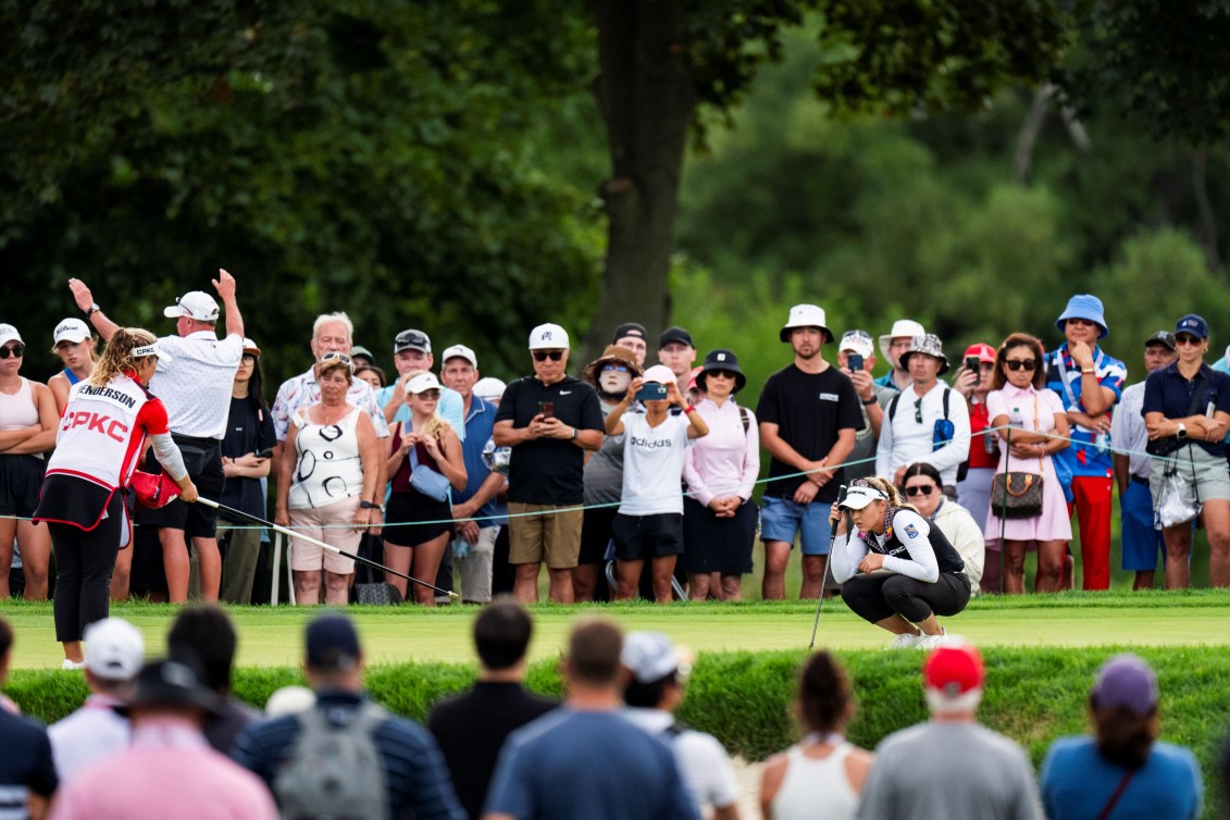 Brooke Henderson squats to study the green