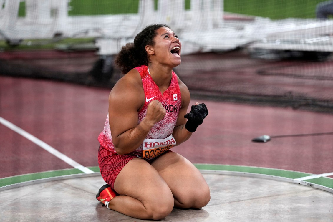 Camryn Rogers pumps her fists while on her knees in the throwing circle