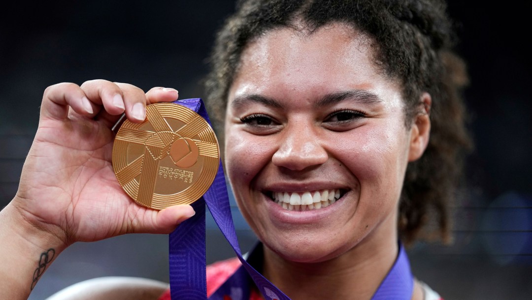 Camryn Rogers smiles while holding a gold medal up by her face
