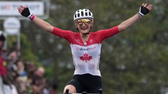 Magdeleine Vallieres in red and white road cycling outfit raises her arms in victory