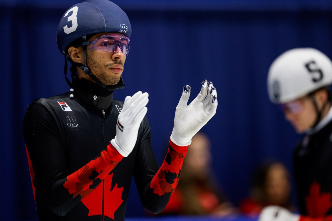 William Dandjinou in black and red speed skating suit claps his hands