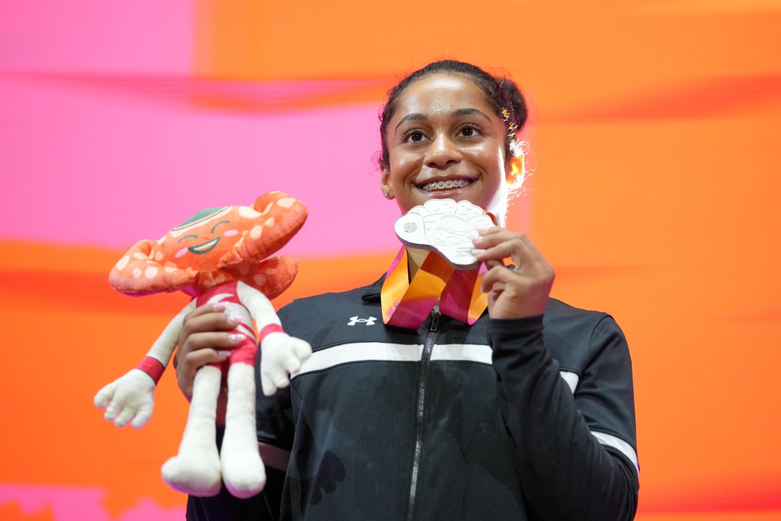 Wearing a black jacket Lia-Monica Fontaine smiles holding her silver medal and mascot plushy