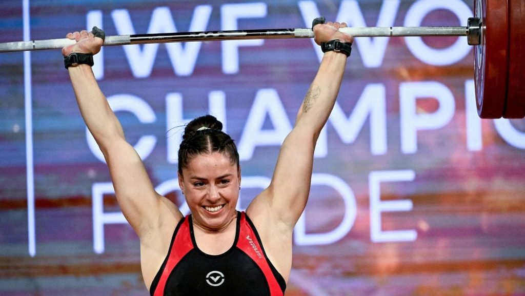 Maude Charron smiles while lifting barbell above her head