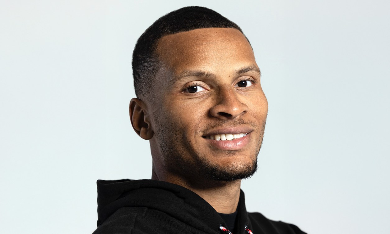 Andre De Grasse against a white background smiling looking forwards.