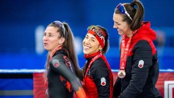 Ivanie Blondin, Valerie Maltais and Isabelle Weidemann stand in a row with big smiles in black skin suits