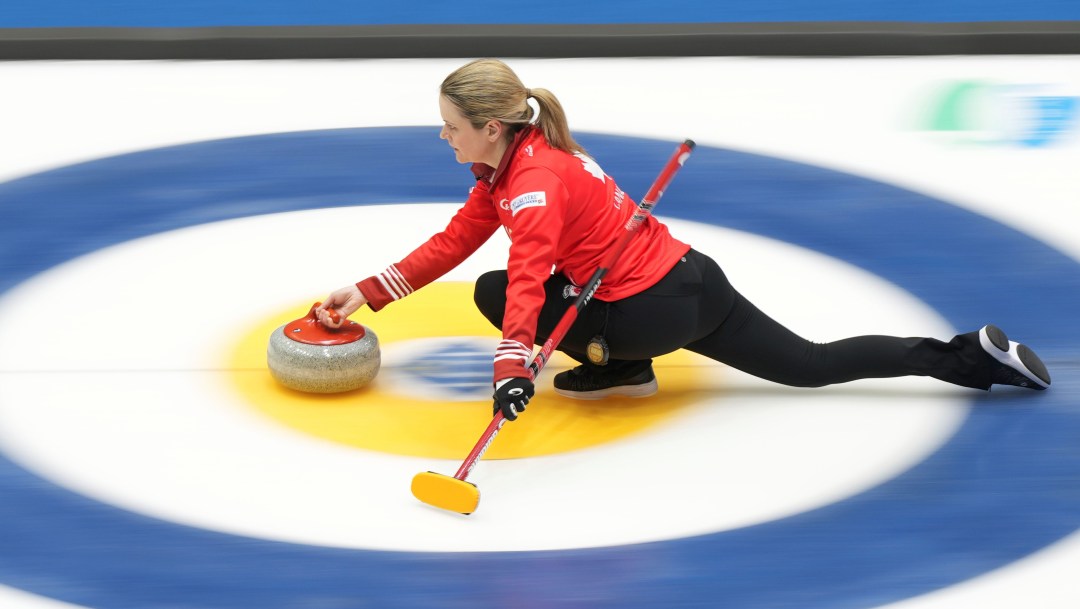 Tracy Fleury in a red jacket slides across the rings as she prepares to throw a stone