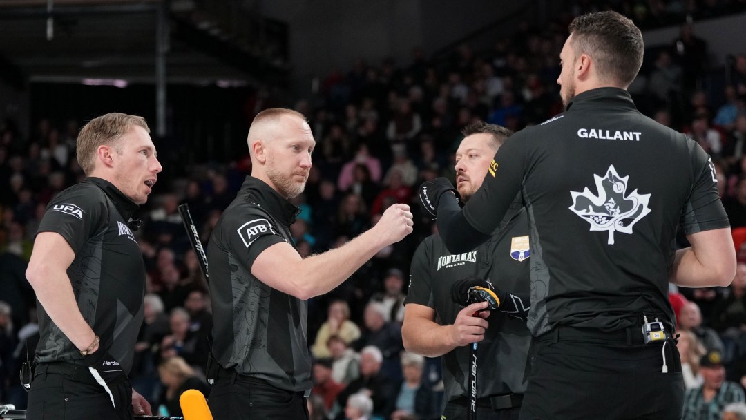 Four male curlers dressed in black fist pump each other