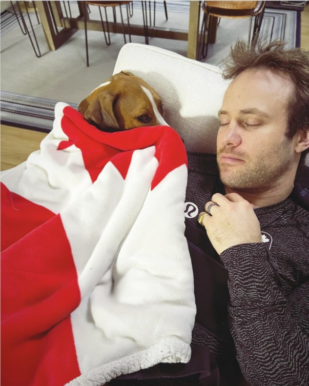 Kevin Drury sleeps next to his dog covered in a Canada flag blanket 