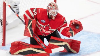 Goaltender in red Canada uniform makes a glove save