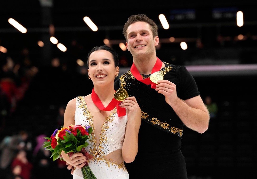 Lia Pereira in a white dress and Trennt Michaud in a black shirt hold their gold medals 