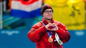 Laurent Dubreuil, with a bronze medal around his neck, makes a heart-shaped sign with his hands.