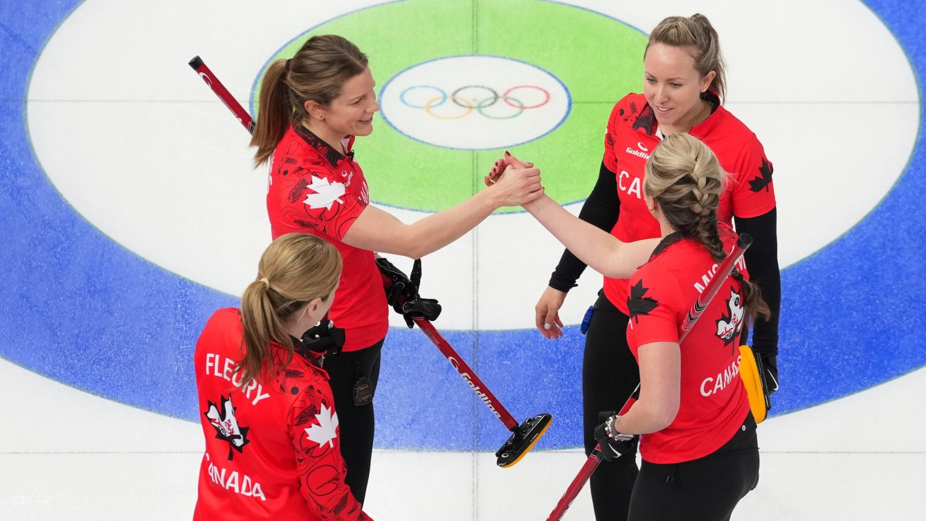 Sarah Wilkes, Tracy Fleury, Rachel Homan, and Emma Miskew of Team Canada compete in a women’s curling game against Denmark at the Milano Cortina 2026 Olympic Winter Games, sweeping and delivering a stone on the ice in Cortina.