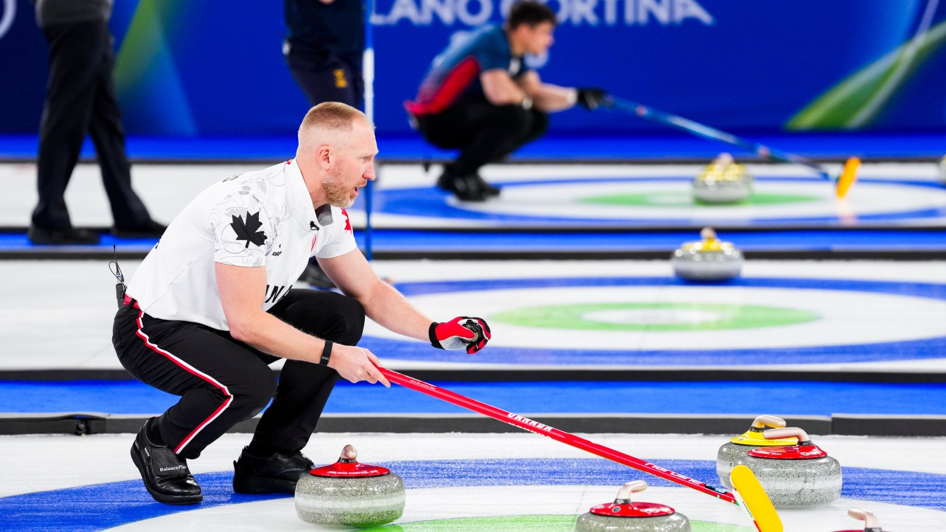 Team Canada curler Brad Jacobs squats on the ice, as he calls next shot against Switzerland.