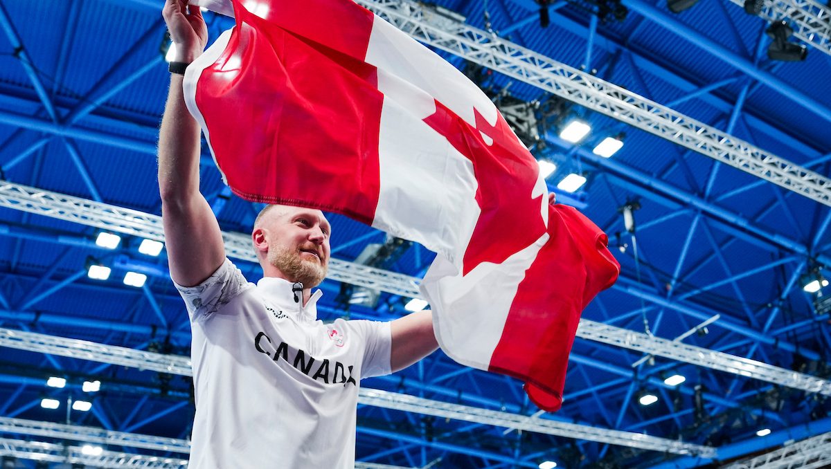 Brad Jacobs lifts Canadian flag in celebration.