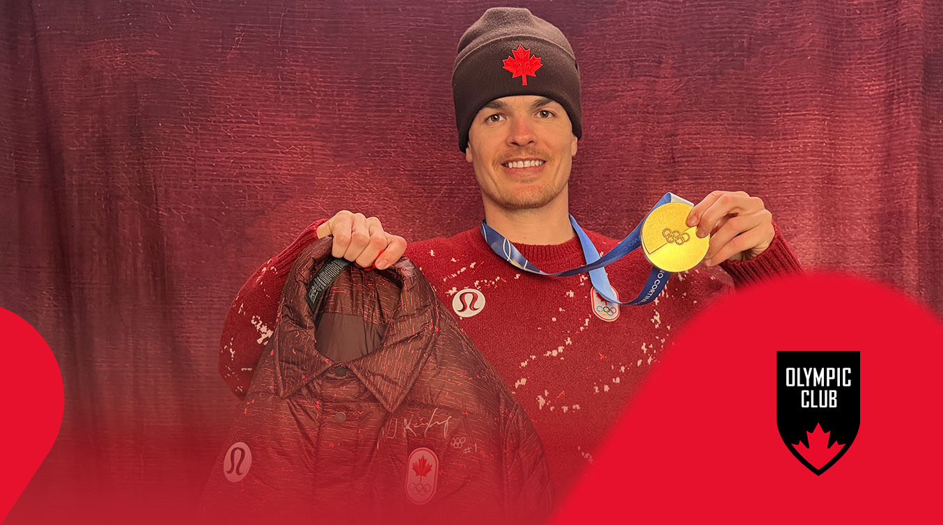 Mikael Kingsbury smiling and holding a Team Canada jacket and a gold medal