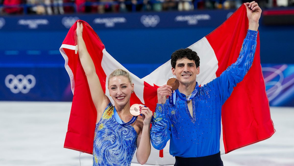 Piper Gilles and Paul Poirier hold their bronze medals and a Canadian flag