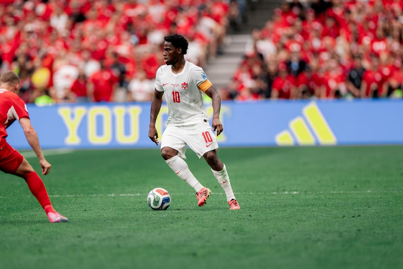 Canada's Jonathan David dribbles the ball against a Switzerland opponent in a FIFA World Cup match on Wednesday.