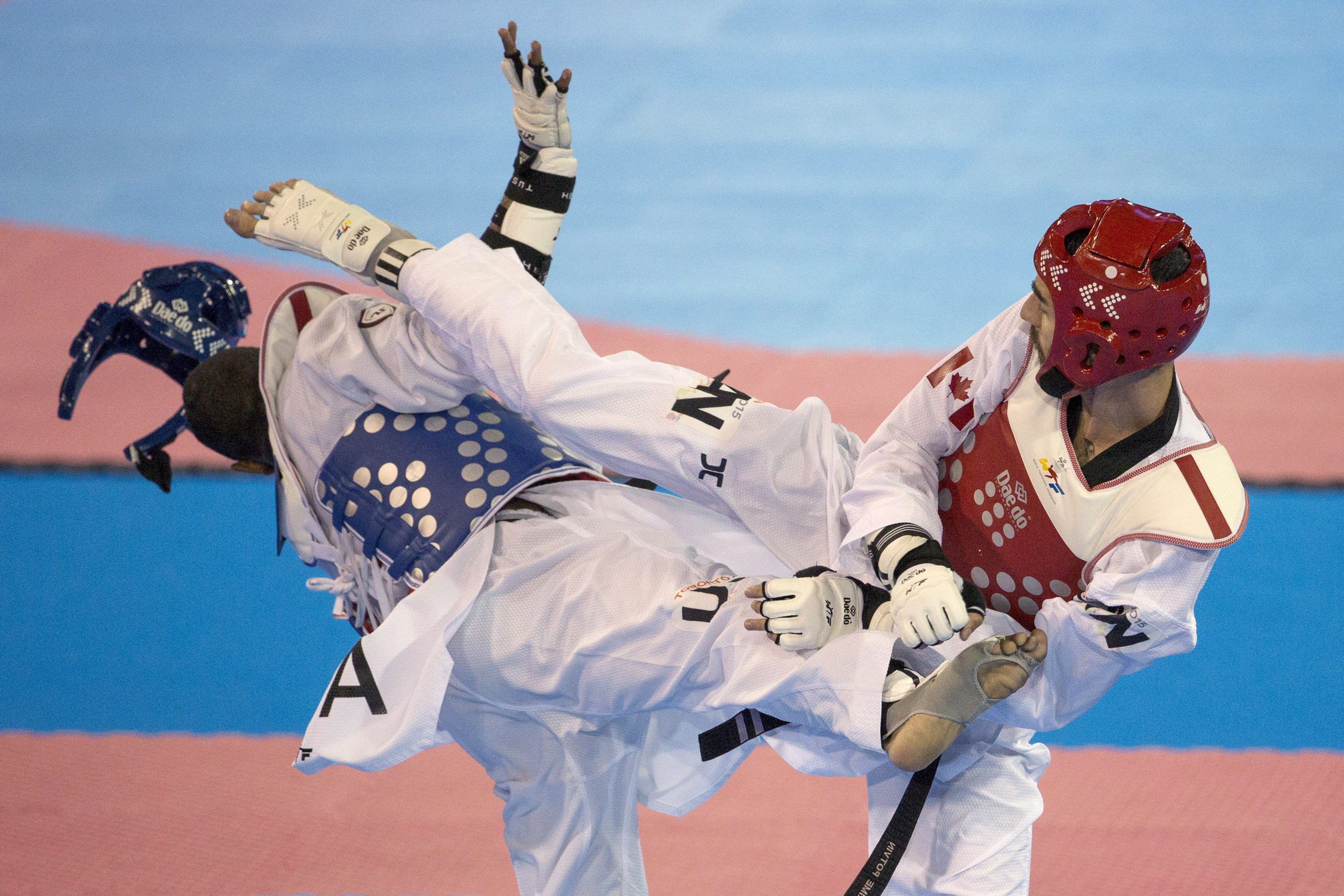 Canada's Maxime Potvin (right) knocks off United States' Terrence Jennings' protective headwear during the men's -68kg semifinal taekwondo contest at the Pan Am games in Mississauga, Ont., on Monday, July 20, 2015. THE CANADIAN PRESS/Chris Young