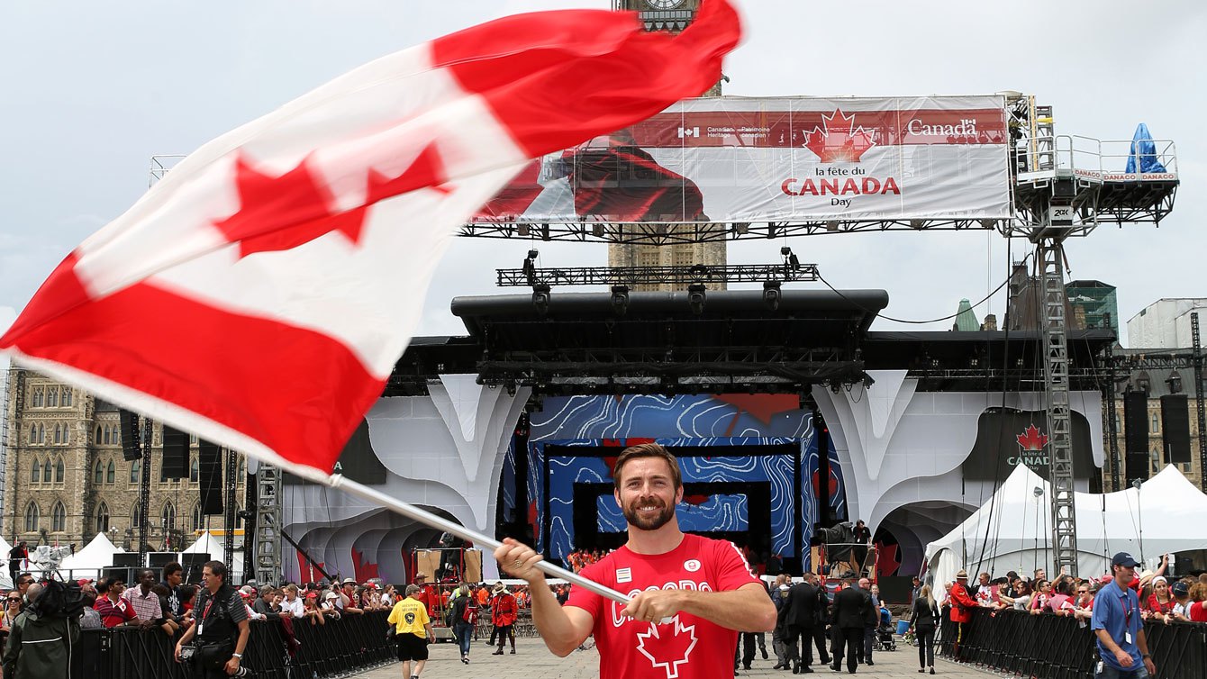 Mark Oldershaw agite le drapeau avant les célébrations de la fête du Canada sur la Colline du Parlement, le 1er juillet 2015 (Greg Kolz pour l’Équipe olympique canadienne).
