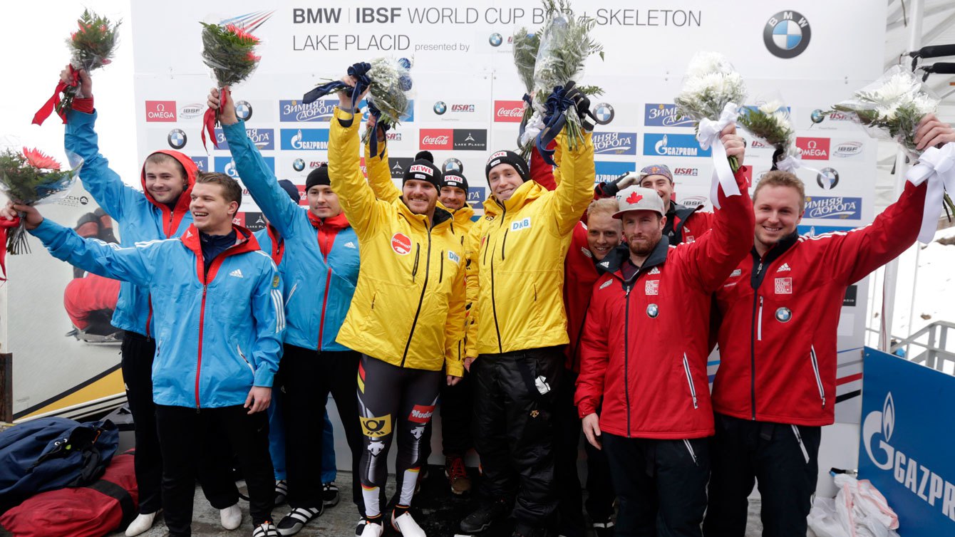 Les équipages de la Russie (en bleu), de l'Allemagne (en jaune) et du Canada (en rouge) lors de la remise des médailles après l'épreuve du bob à quatre de la Coupe du monde BMW IBSF de Lake Placid, le 9 janvier 2016. 