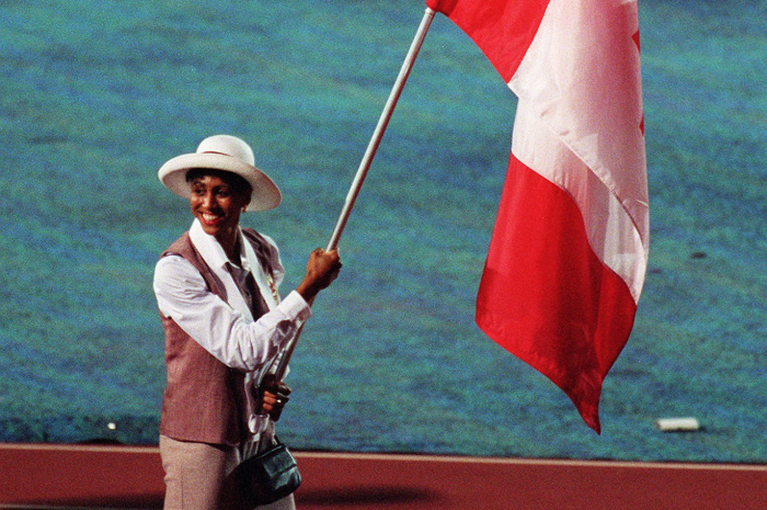 Charmaine Crooks, souriante, portant le drapeau.