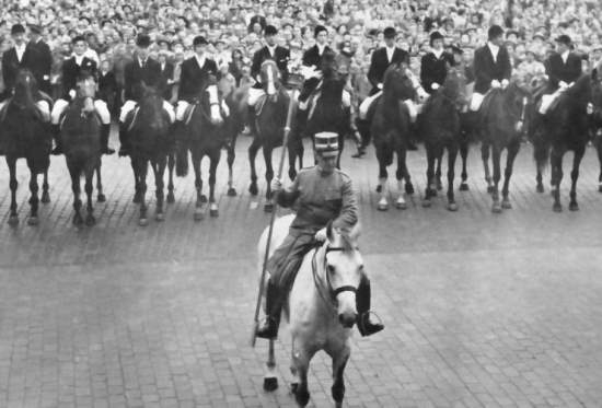 Un homme à cheval mène une rangée d'une dizaine de cavaliers à cheval.