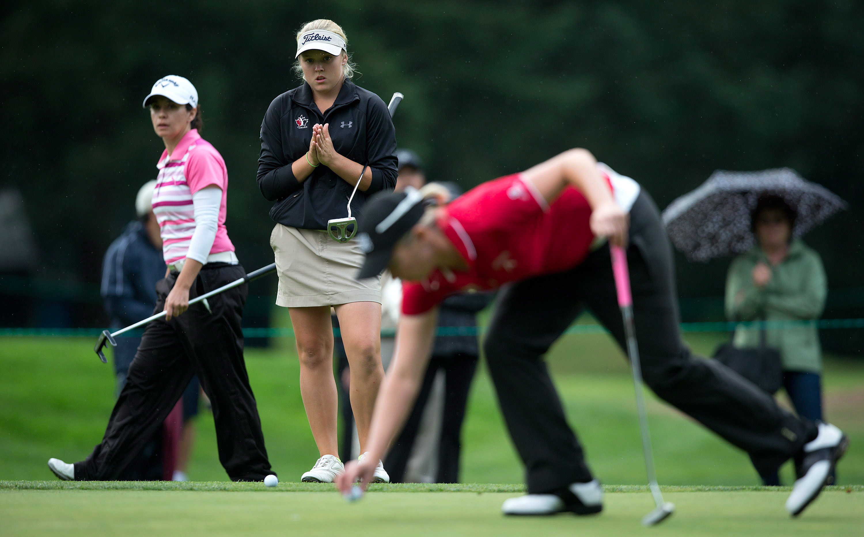 Fourteen-year-old Brooke Henderson, second left, of Smiths Falls, Ont., waits to putt on the 17th hole as Alena Sharp, right, of Hamilton, Ont., places her ball and Mo Martin, left, of Altadena, Calif., looks on during the first round of the CN Canadian Women's Open LPGA golf tournament at the Vancouver Golf Club in Coquitlam, B.C., on Thursday August 23, 2012. THE CANADIAN PRESS/Darryl Dyck