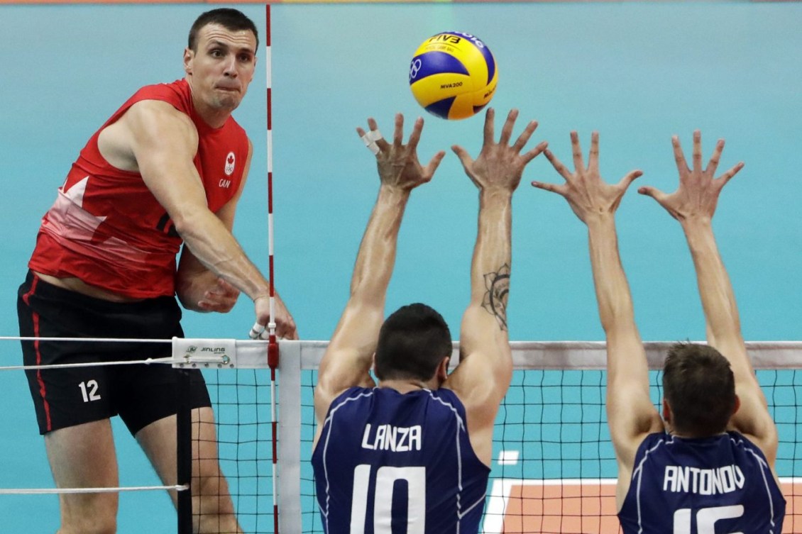 Gavin Schmitt, à gauche, effectue un smash contre Filippo Lanza, au centre, et Oleg Antonov aux Jeux olympiques de Rio, le 15 août 2016. (AP Photo/Matt Rourke)