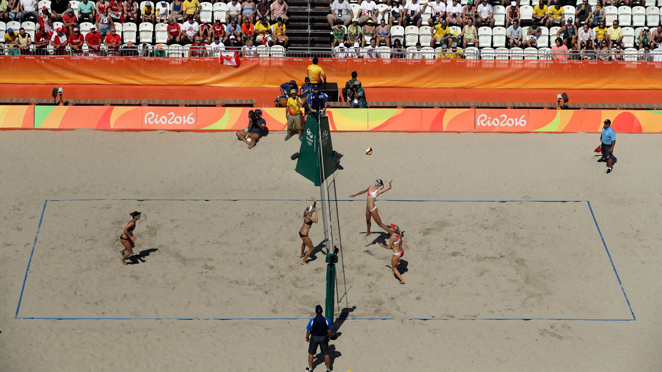 Sarah Pavan (au centre) effectue un smash contre Jamie Broder et Kristina Valjas (au filet) lors du match de quarts de finale opposant les deux équipes canadiennes au tournoi olympique féminin de volleyball de plage à Rio, le 13 août 2016. (Photo AP/Marcio Jose Sanchez)