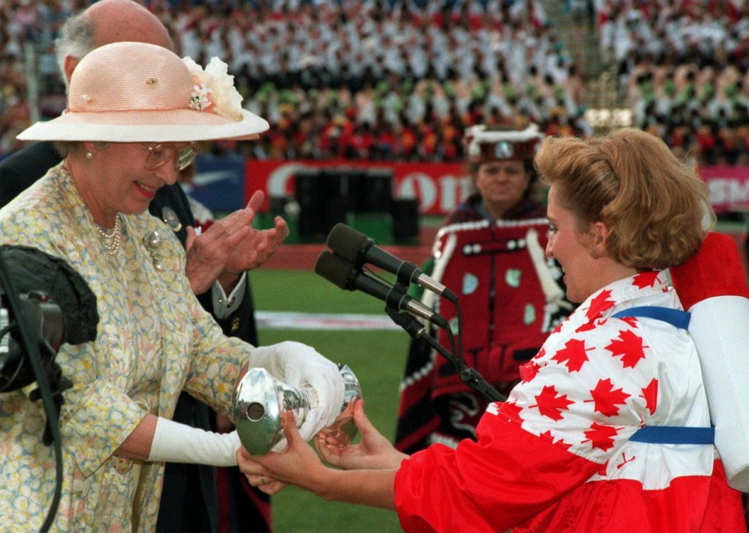 La médaillée d'or Myriam Bedard tient la main de la Reine Elizabeth II lors de la cérémonie d'ouverture des Jeux du Commonwealth de 1994, à Victoria. (CP PHOTO/Andrew Vaughan)