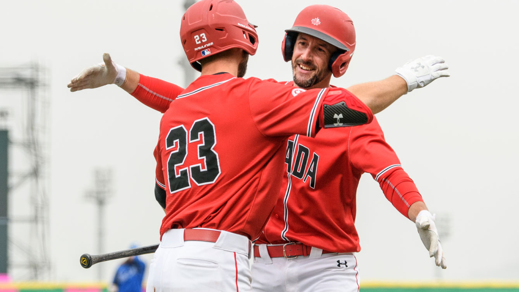 Deux coéquipiers canadiens de baseball se font un câlin après une victoire