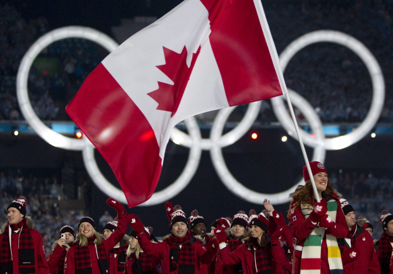 Clara Hughes porte le drapeau canadien, l'équipe canadienne derrière elle.