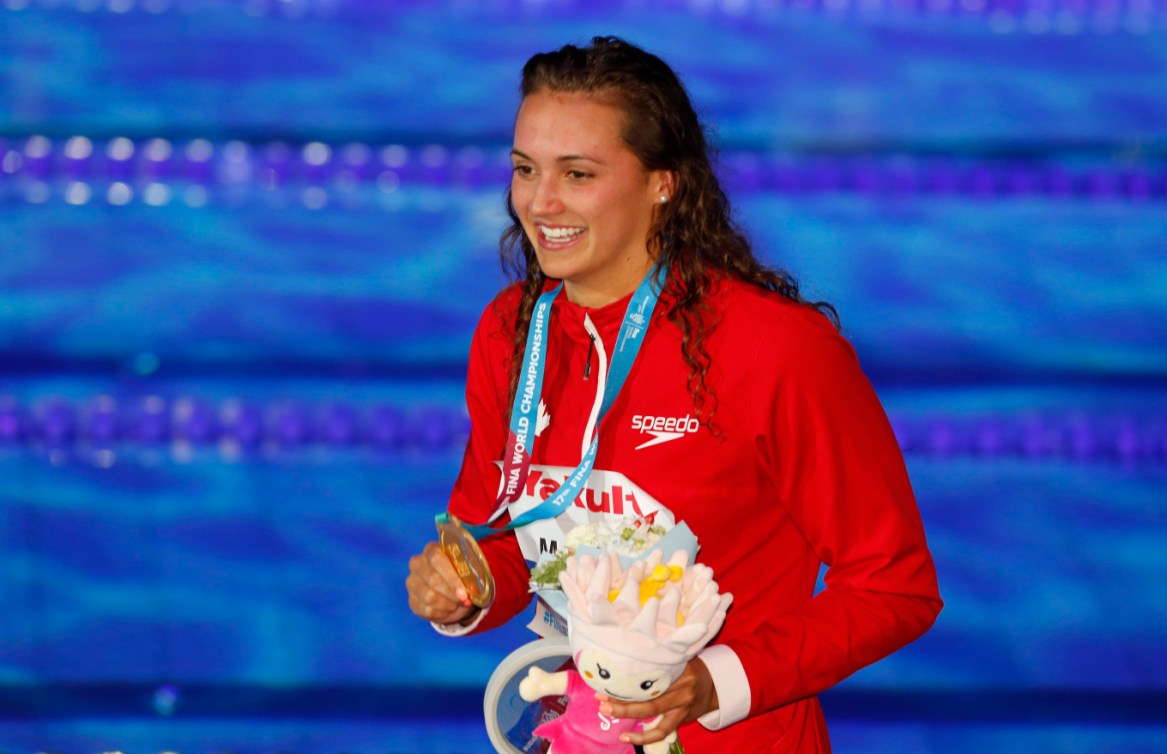 Kylie Masse, souriante, montre sa médaille